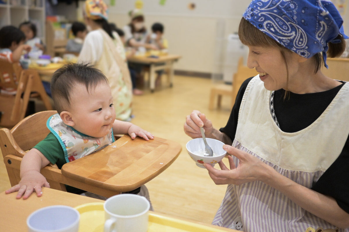 食事を手伝う保育士と園児(ひよこルーム武蔵新城保育園)
